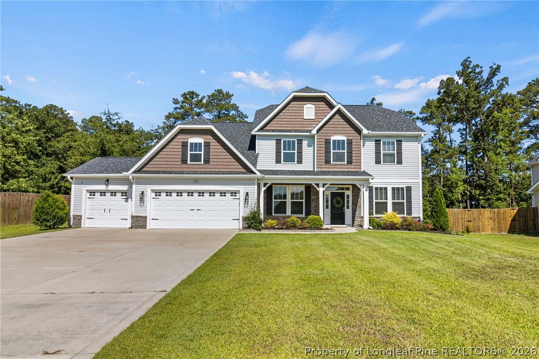 Two-story house with two garage doors, a covered porch, and a broad lawn.