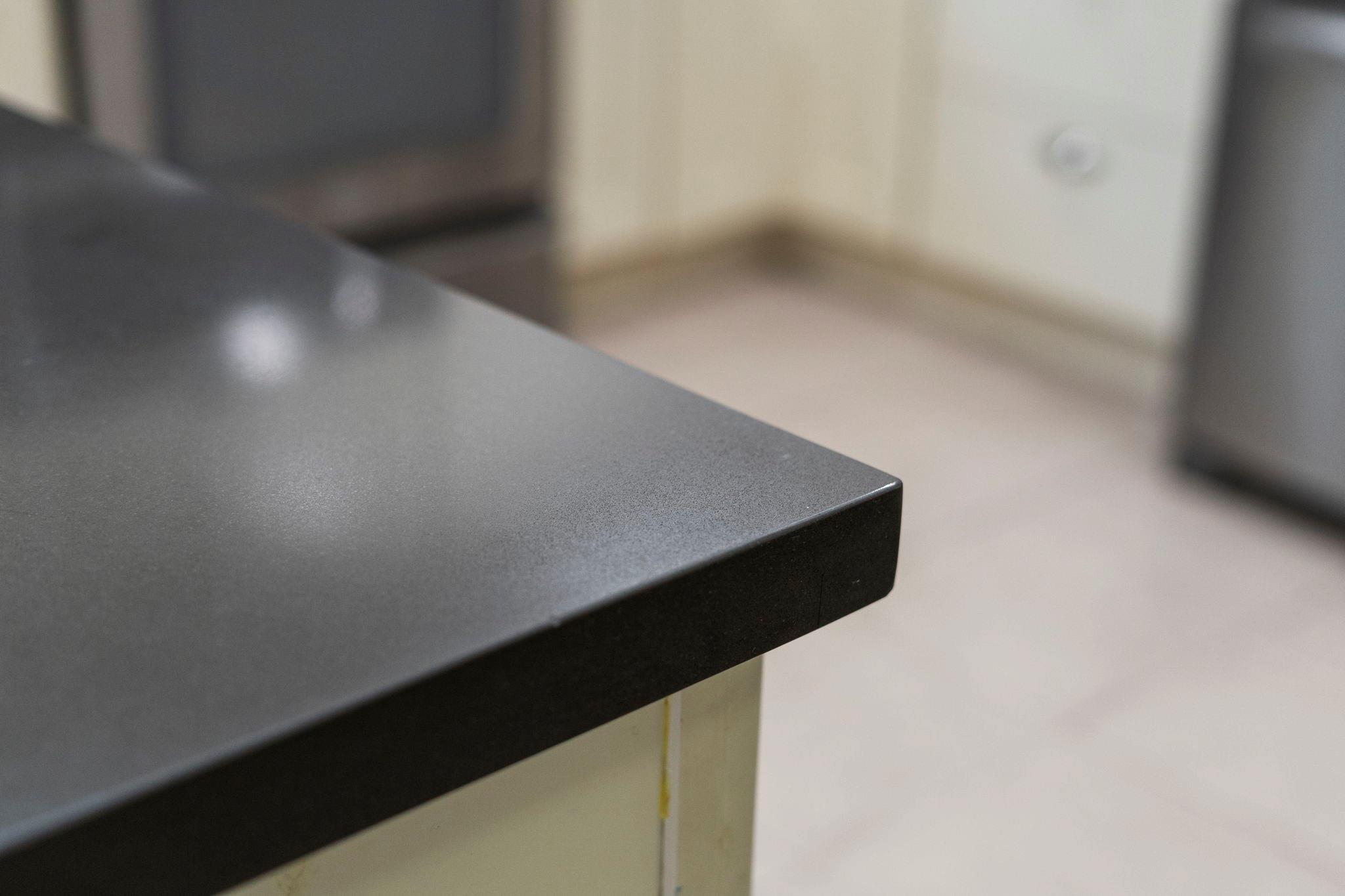 Dark speckled countertop with a squared edge above a light cabinet