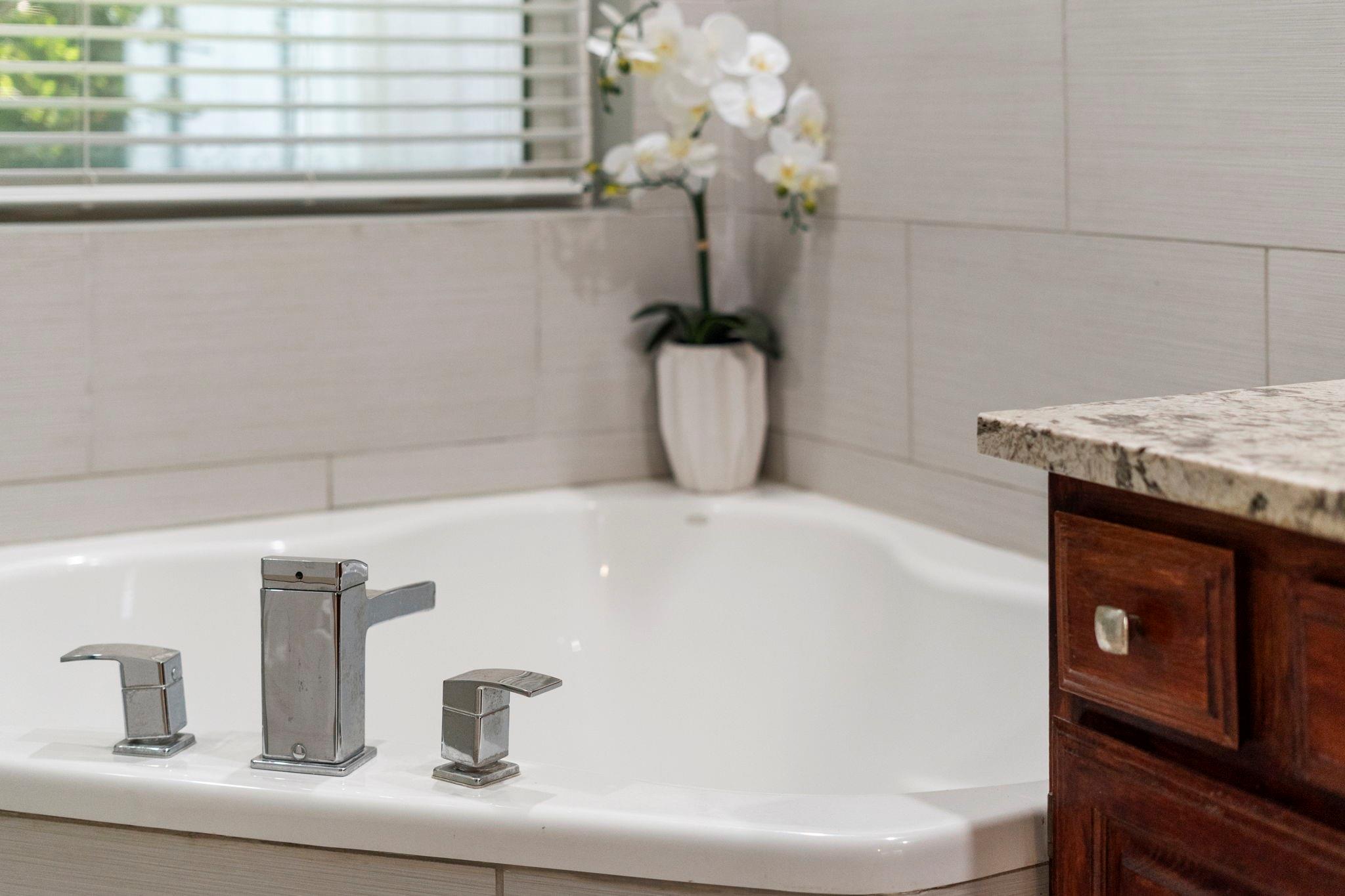 Bathroom vanity with a modern chrome faucet, dark wood cabinetry, and a white orchid beside the window.