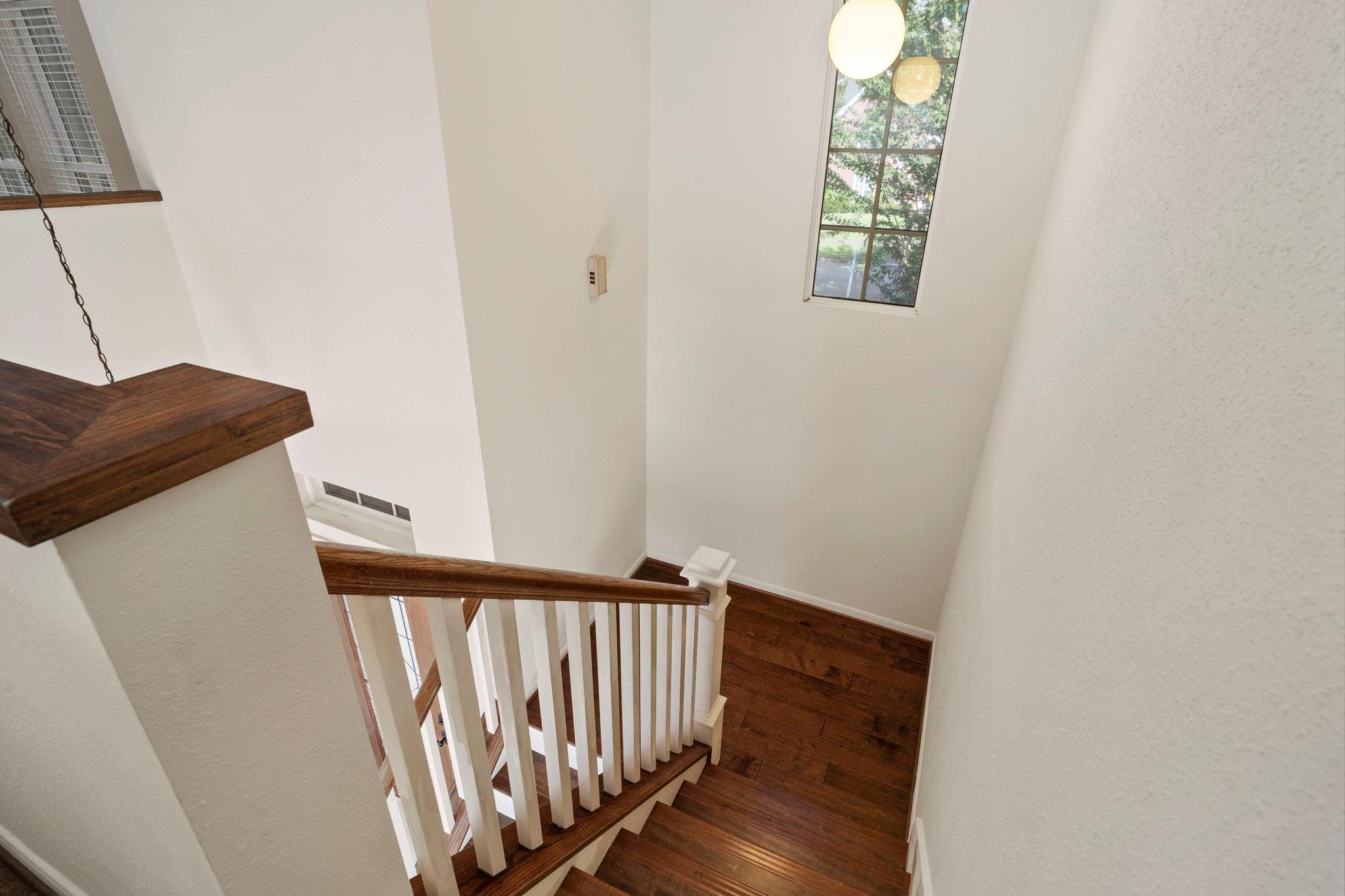 Two-story staircase with dark wood treads, white balusters, and a tall window.