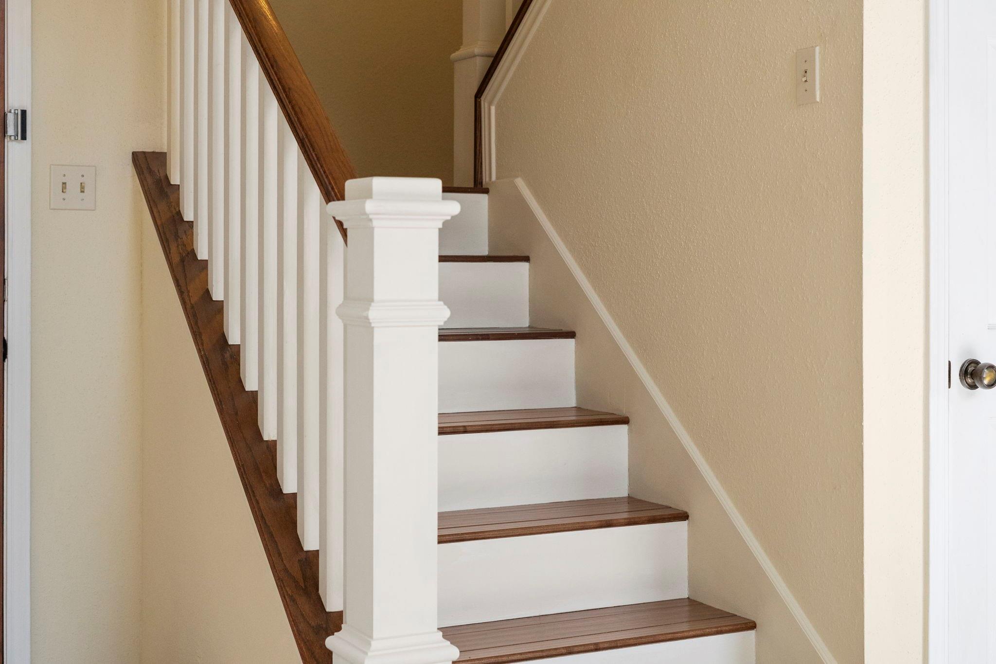Staircase with dark wood treads and handrail, white risers, and white balusters.