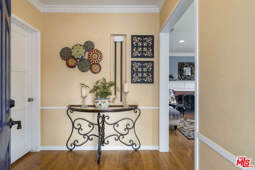 Furnished entryway with a wrought-iron console table, colorful wall art, and a view into the living room.