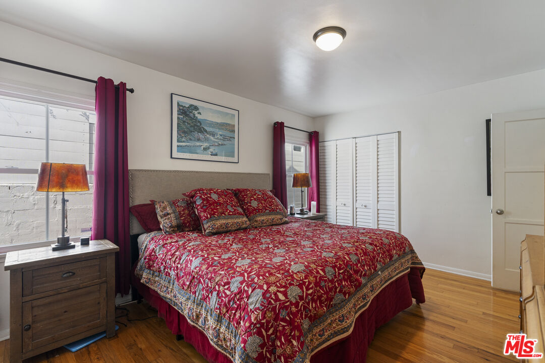 Bedroom with red floral bedding, matching curtains, and hardwood floors.