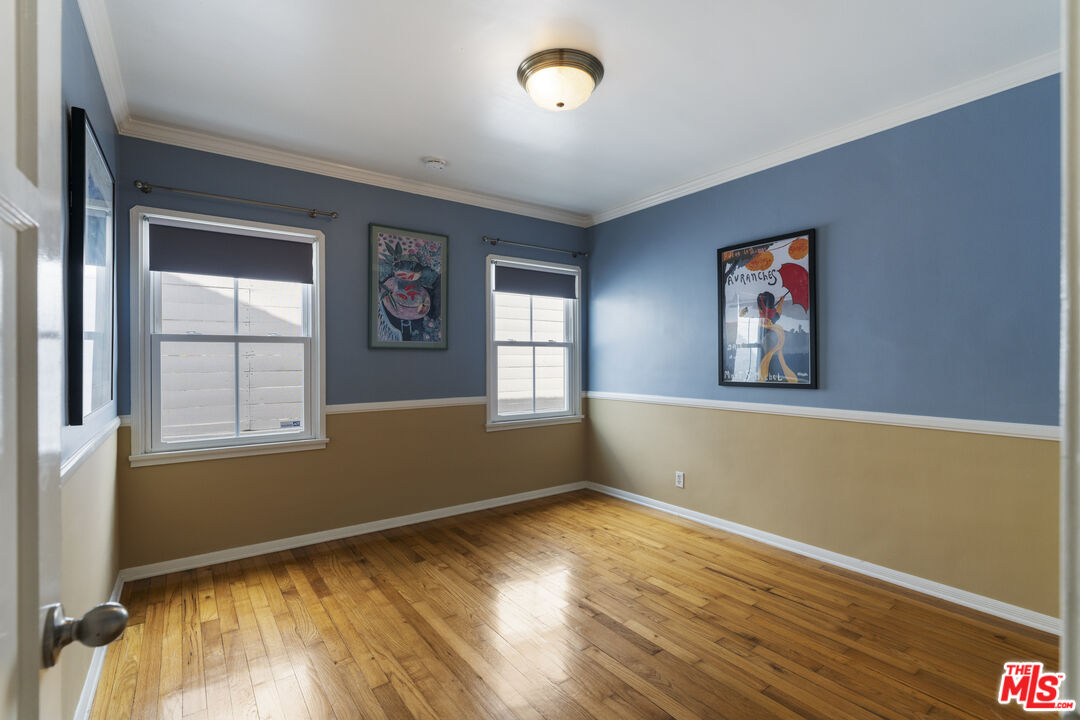 Empty room with polished hardwood floors, two-tone blue and tan walls, and framed artwork.