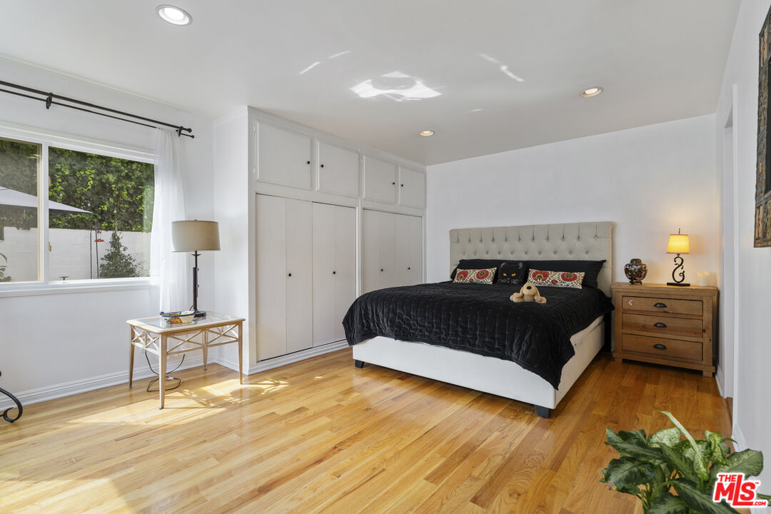 Bedroom with built-in closets, hardwood floors, and a king-size bed beneath a tufted headboard.