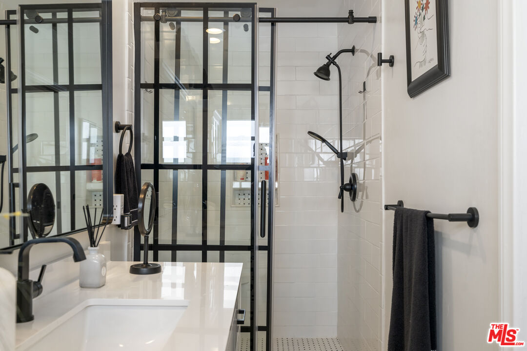 Bathroom with a white vanity and black-framed glass shower enclosure.