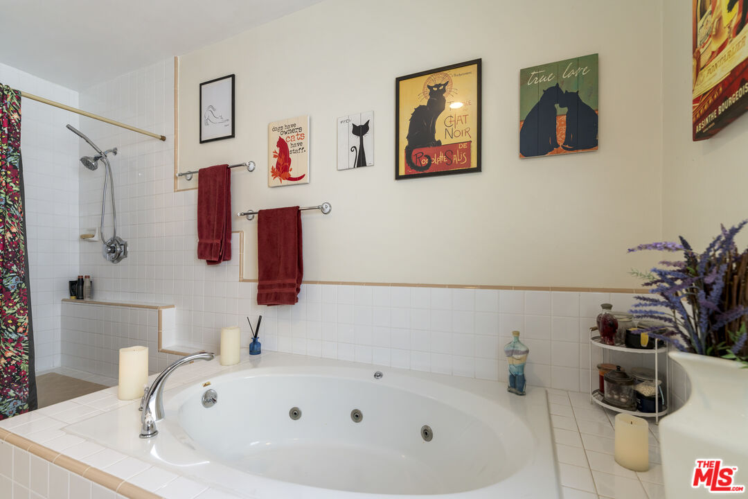 Bathroom with a large jetted tub, white tile, burgundy towels, and cat-themed wall art.