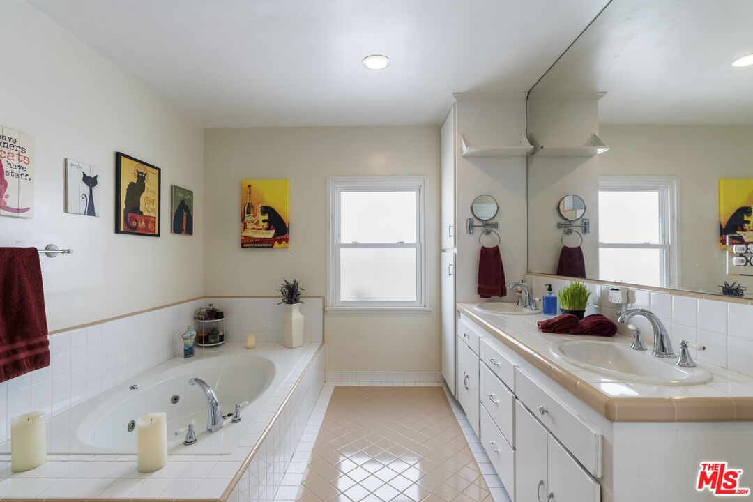 Bathroom with a jetted tub, long double-sink vanity, and framed cat artwork.