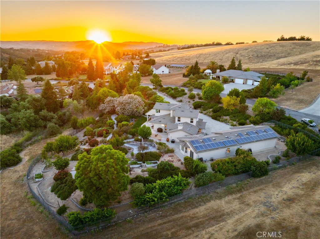 Aerial view of a rural property with solar panels and landscaped grounds at sunset.