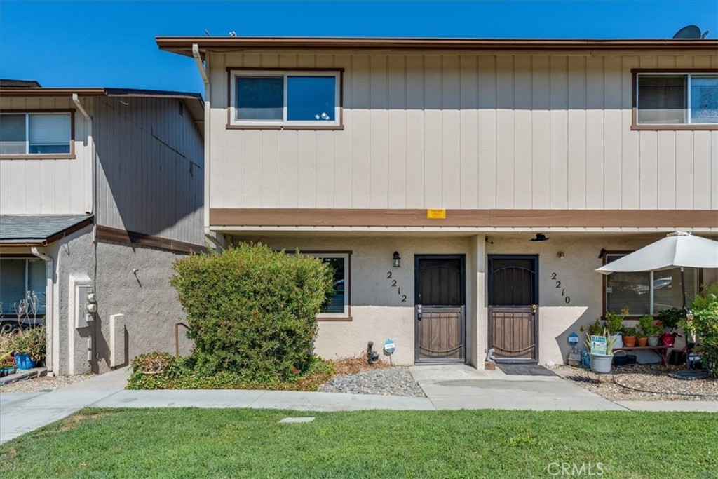 Two-story attached residences with separate front entrances, a large shrub, and a small patio.