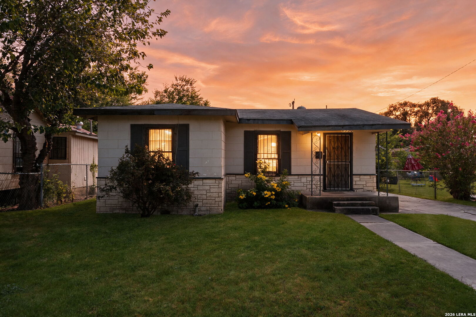 Single-story house with a stone-accented facade and glowing windows at dusk.