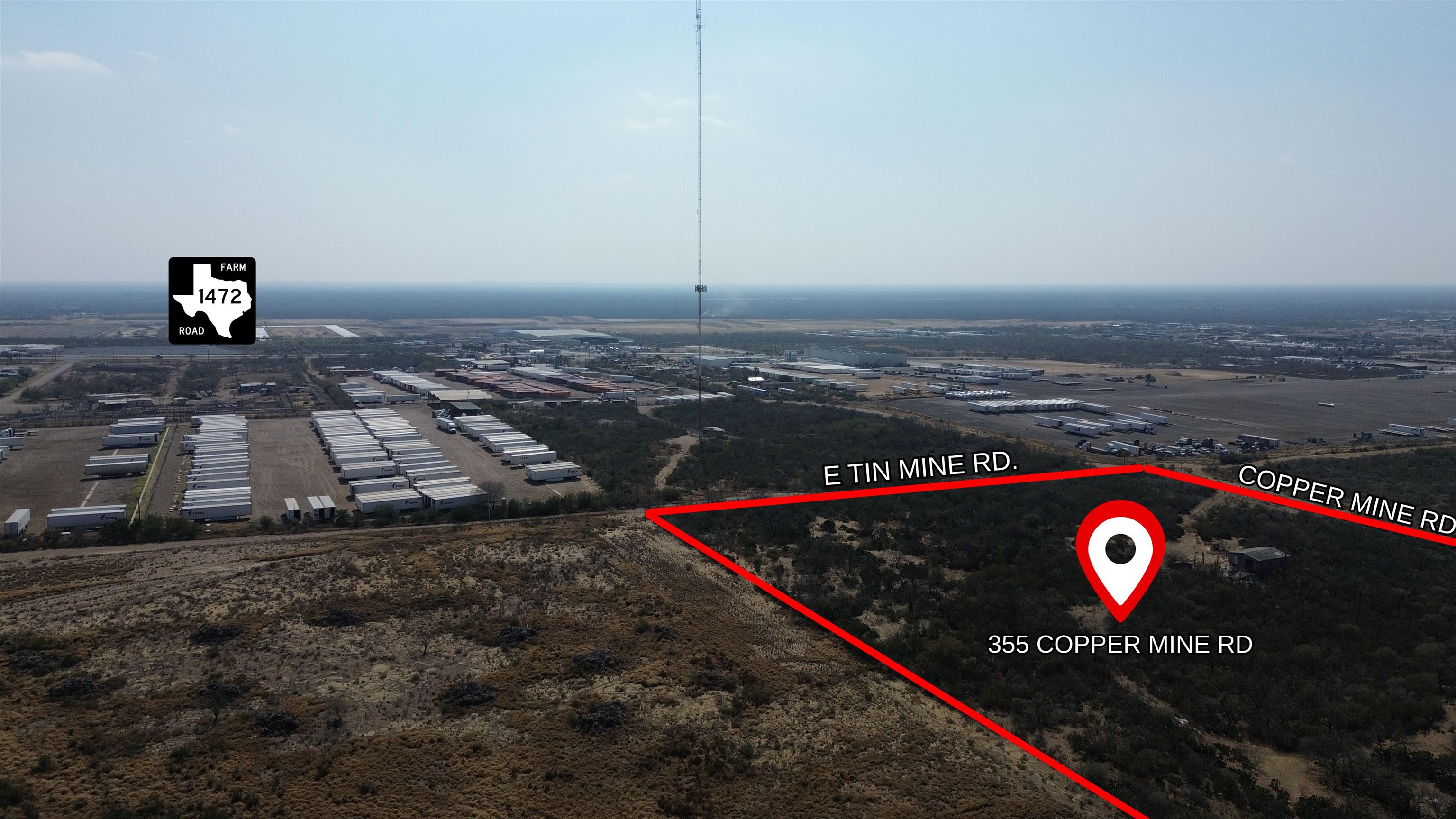 Aerial view of the brush-covered parcel at 355 Copper Mine Road, outlined in red beside trailer storage yards.