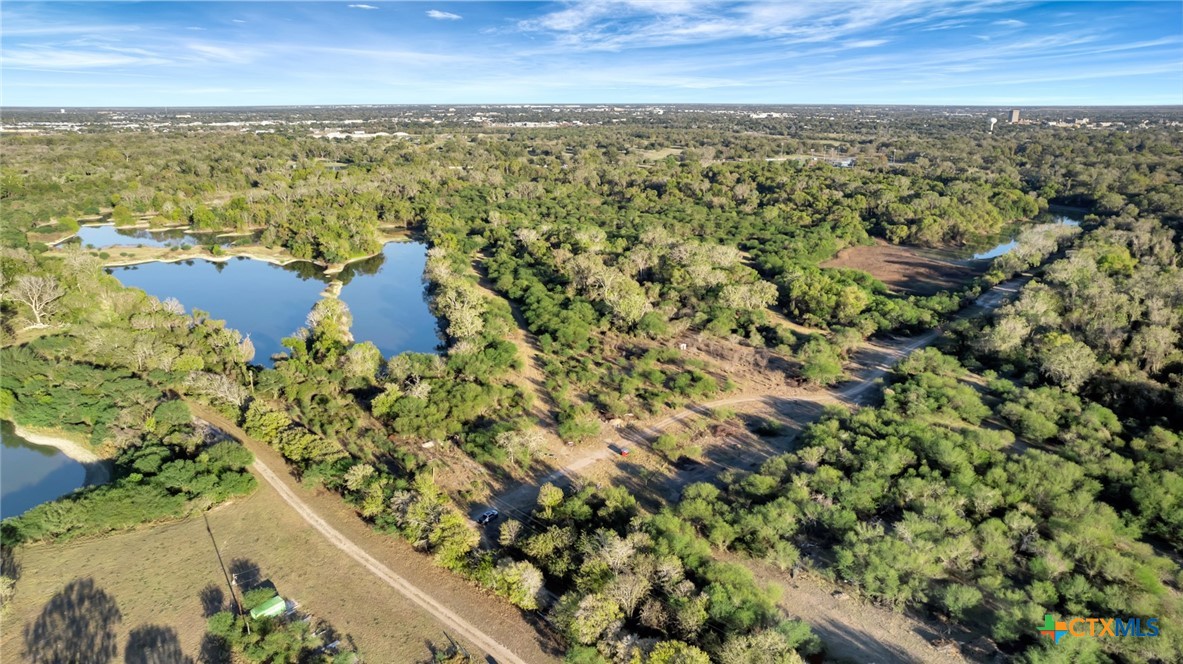 Aerial view of wooded ranch land with ponds, clearings, and dirt roads.