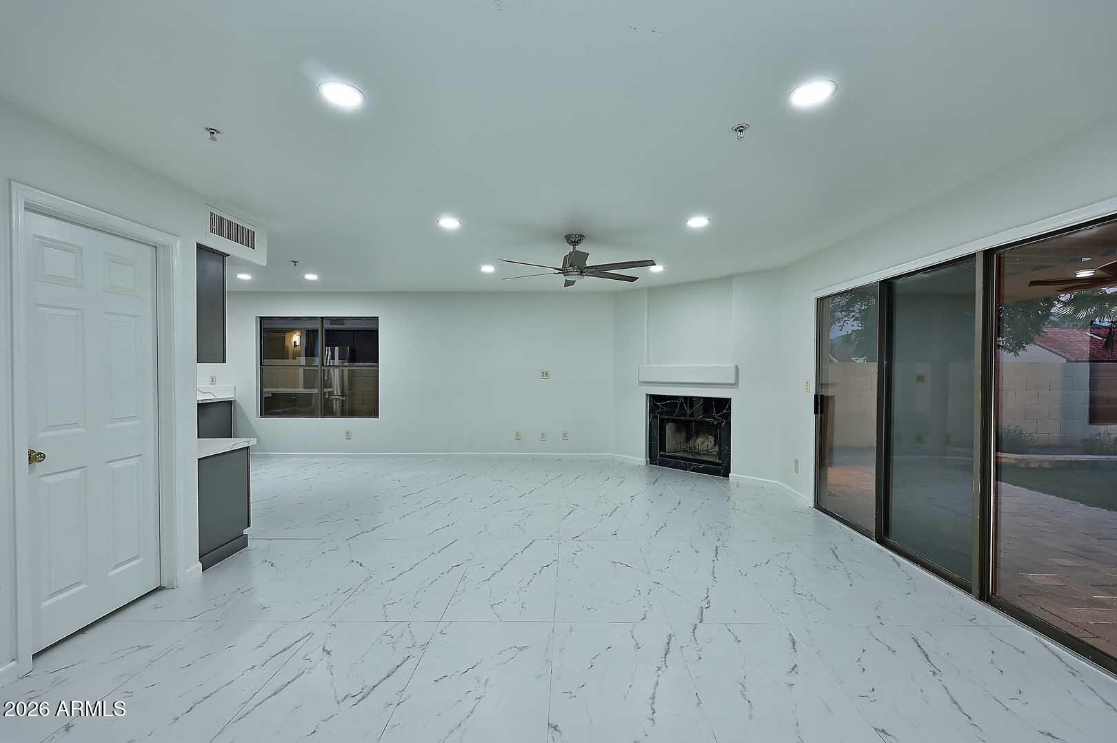 Vacant living room with a fireplace, marble-look tile floors, and sliding glass doors to a patio.