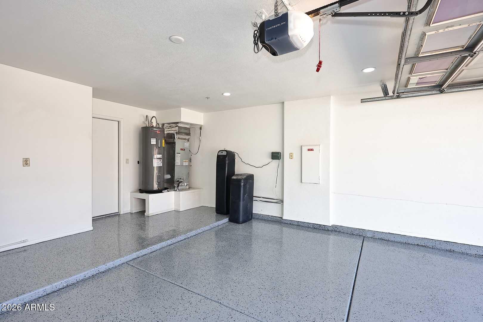 Garage with a speckled epoxy floor, water heater, and water softener.