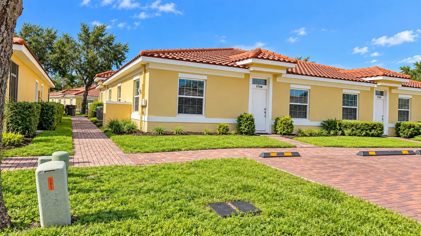 Yellow condominium units with red tile roofs and brick walkways.