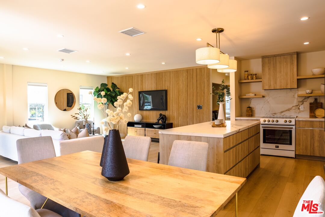 Open-plan kitchen and dining area with a wood table, large island, and warm wood cabinetry.