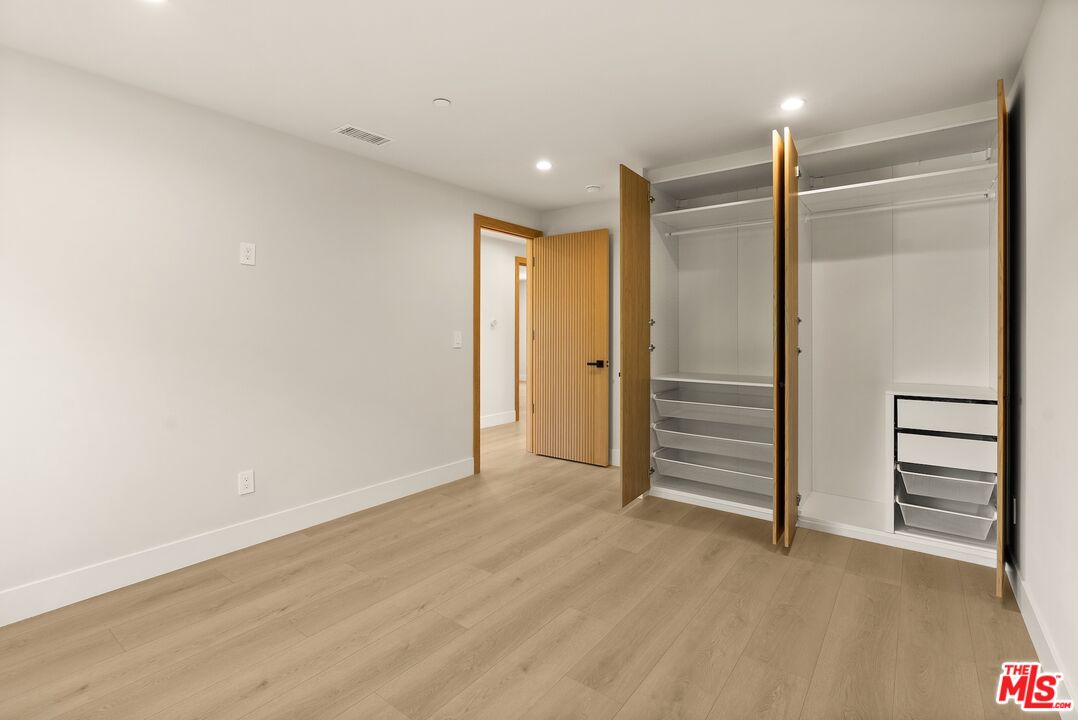 Empty room with light wood floors and open built-in closets