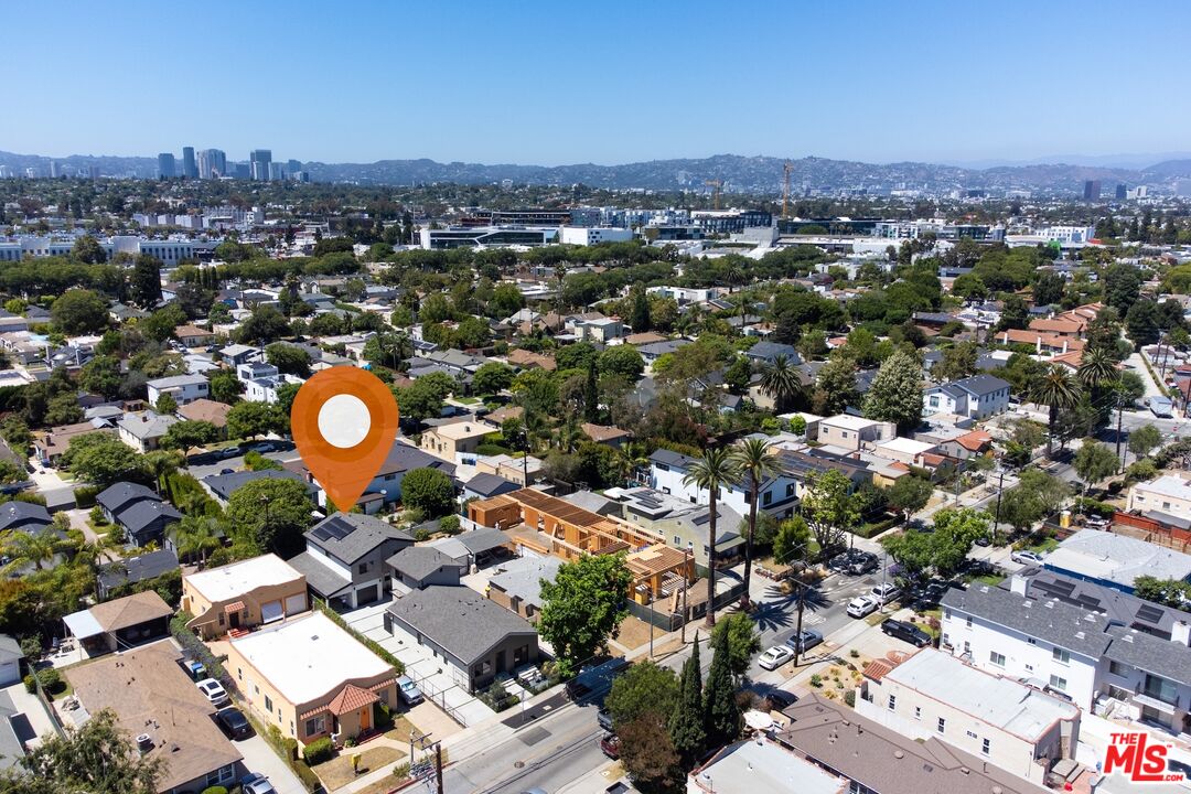 Aerial neighborhood view with an orange marker over a home and a distant city skyline.