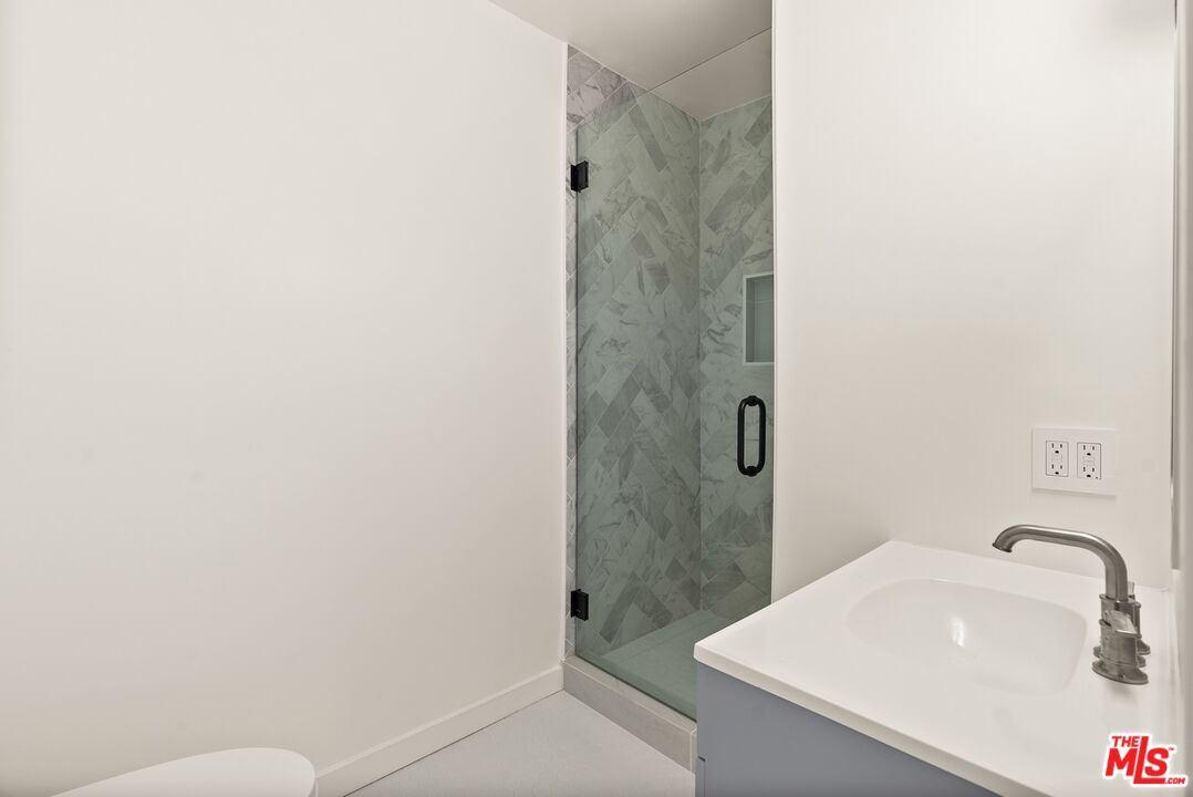 Bathroom with a patterned-tile glass shower and white vanity with chrome fixtures.