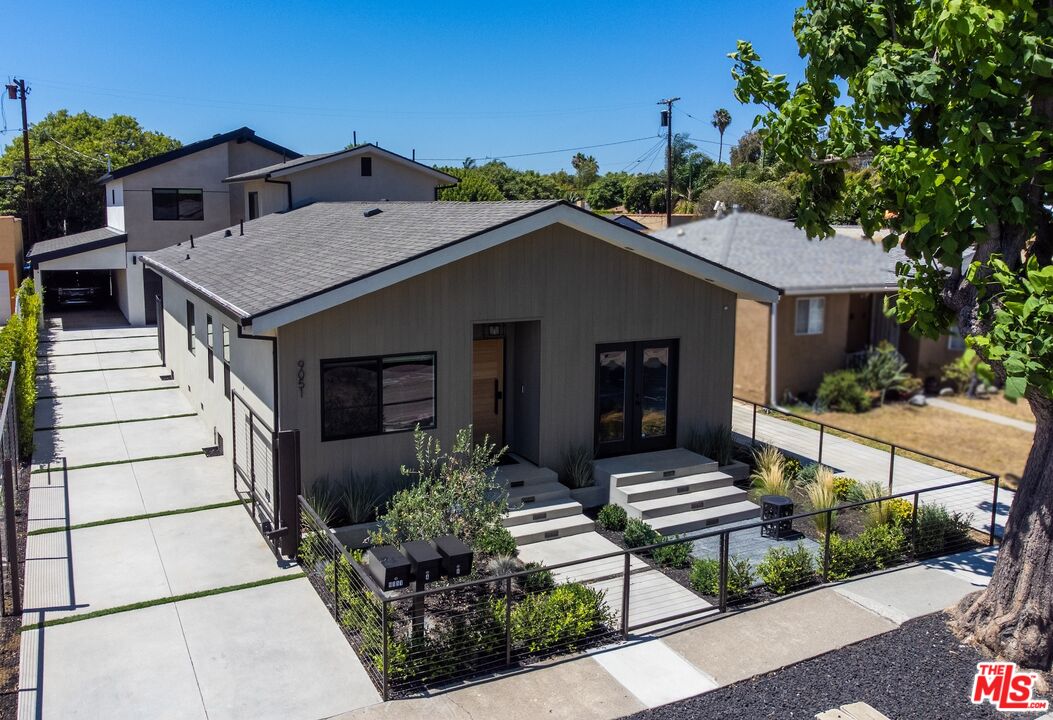 Modern gray home with a front gable, black metal fence, and planted entry beds.