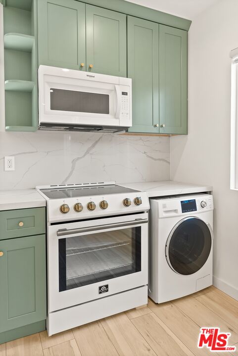 Kitchen with sage green cabinets, a gas range, and a front-loading washer and dryer.