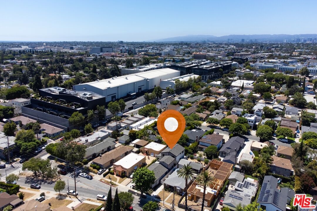 Aerial neighborhood view with an orange map pin among homes and a large commercial complex nearby.