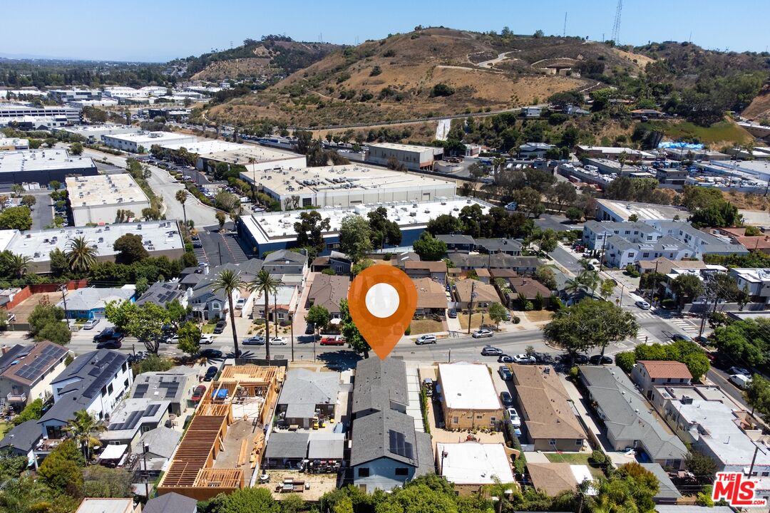 Aerial neighborhood view with a location marker, construction site, and dry hills beyond.
