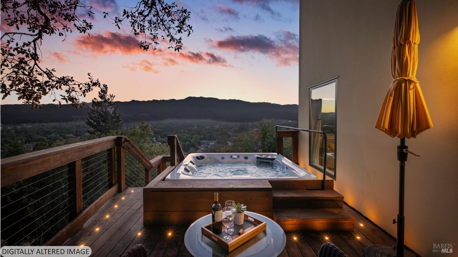 Wooden deck with a hot tub overlooking a wooded valley at sunset.