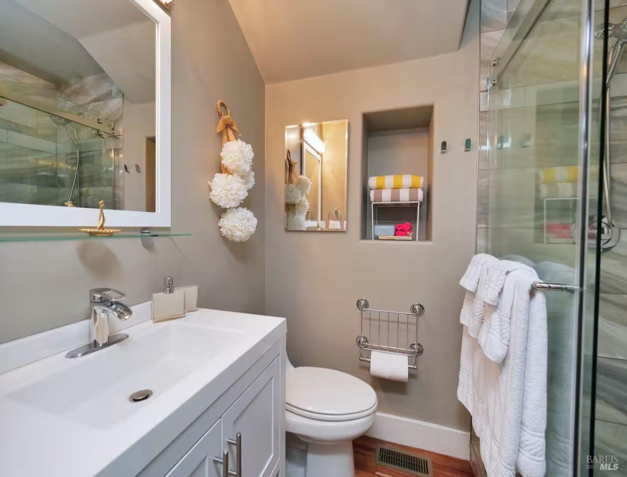 Bathroom with a white vanity, toilet, and glass-enclosed shower.