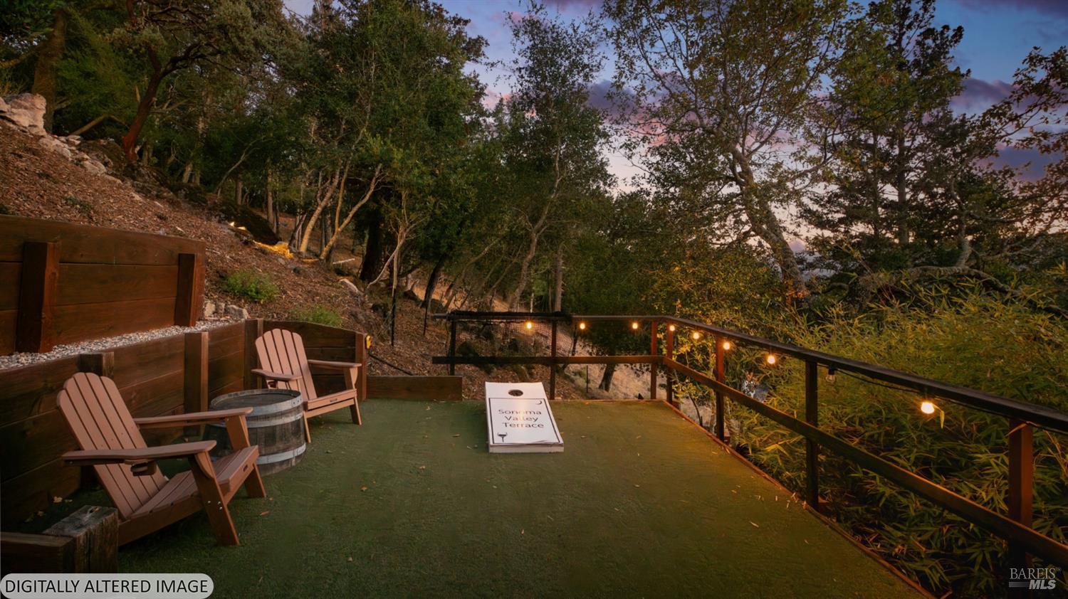 Wooded outdoor terrace with Adirondack chairs, a barrel table, and string lights at dusk.
