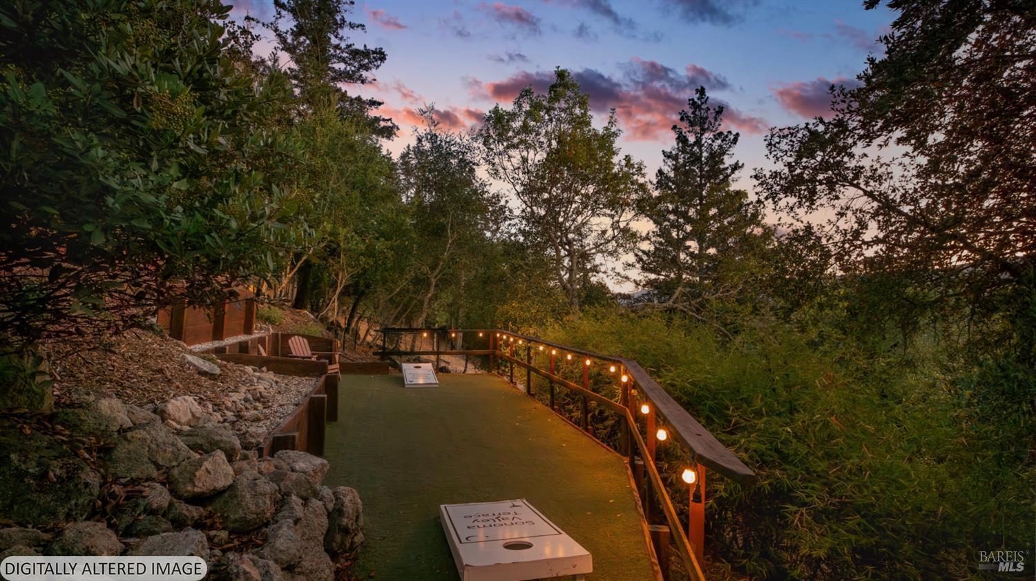 Wooded outdoor patio path with illuminated railing and bench seating at dusk.