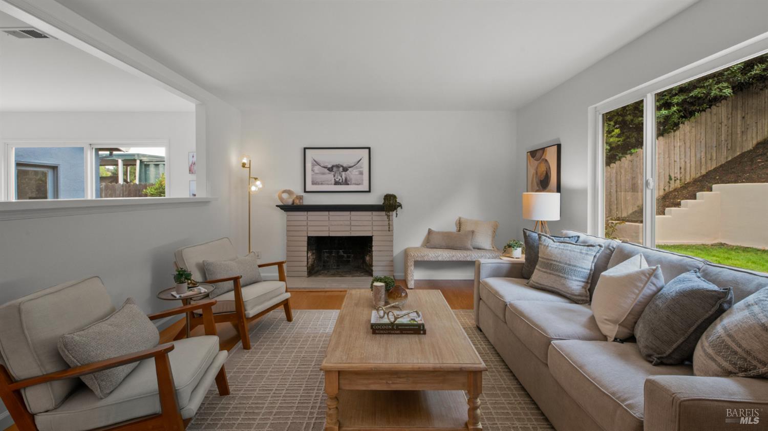 Staged living room with a tiled fireplace, neutral seating, and sliding doors to the yard.