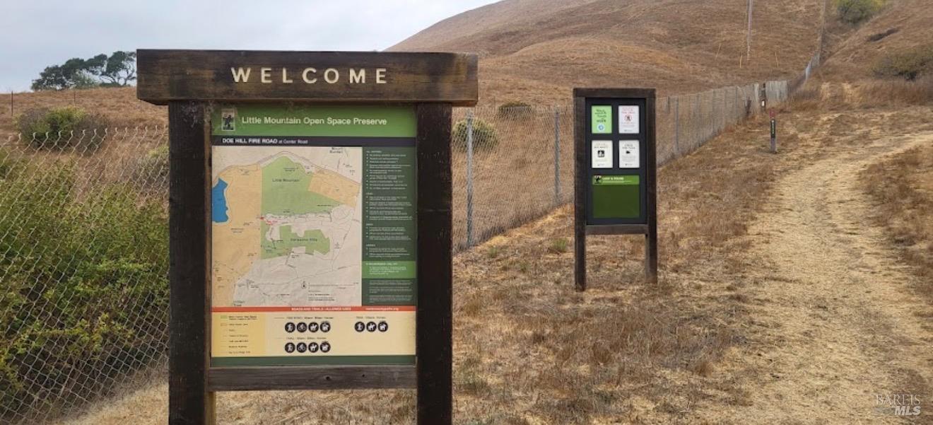 Little Mountain Open Space Preserve entrance with a wooden welcome sign and trail map beside a dry hillside path.