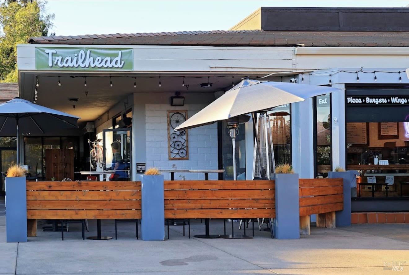 Trailhead restaurant storefront with a fenced outdoor patio and umbrellas.