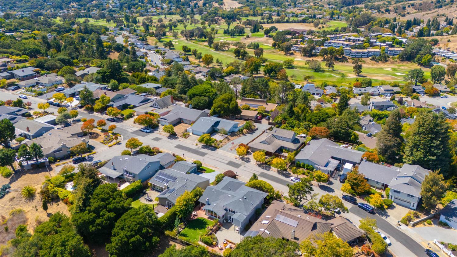 Aerial view of homes and tree-lined streets beside a golf course.
