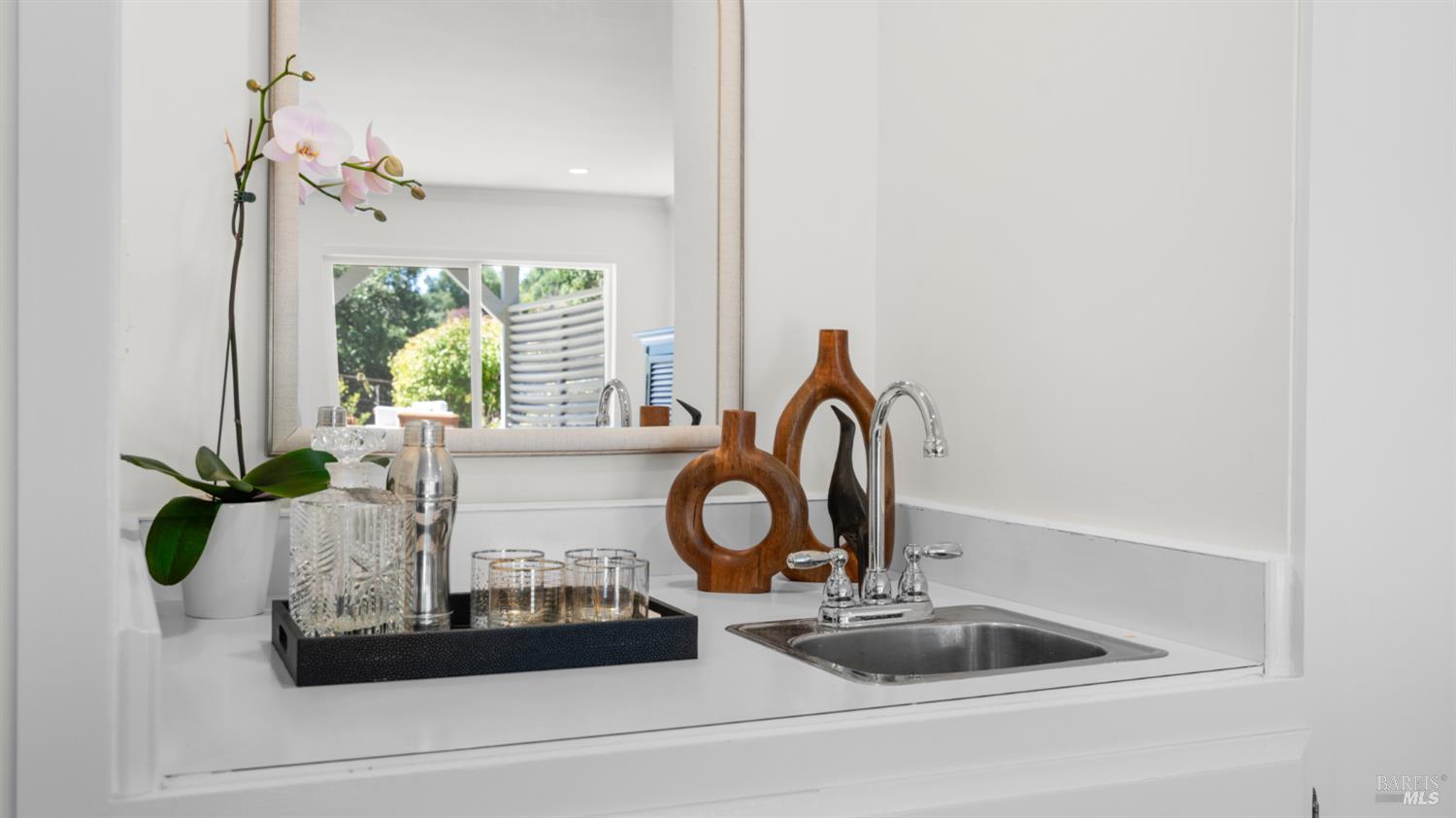 Bathroom vanity with a stainless-steel sink, chrome faucet, large mirror, and orchid.
