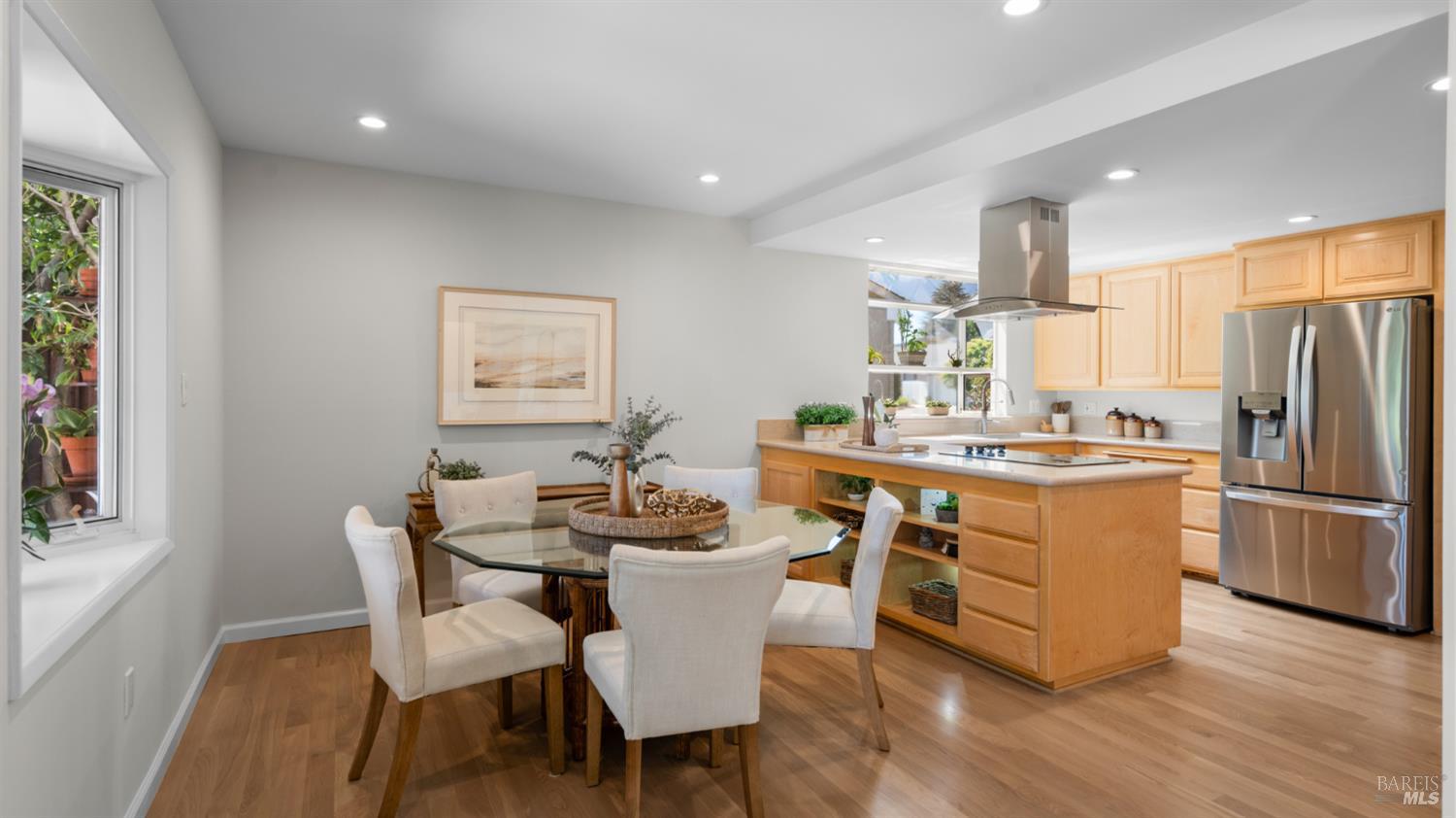 Open kitchen and dining area with a large wood island and glass dining table.