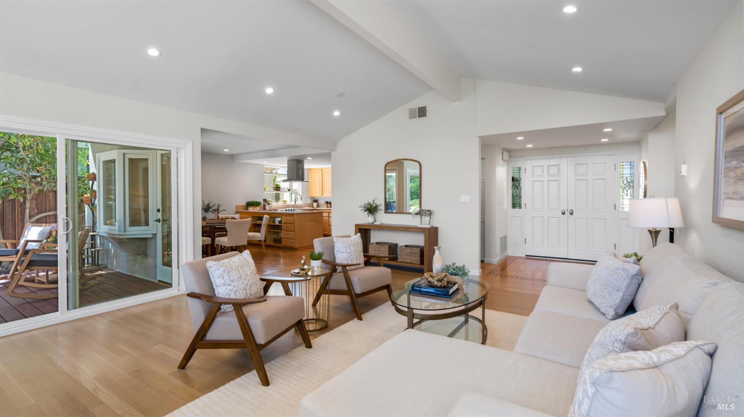 Living room with pale wood floors, a white sectional, and sliding doors to a patio.