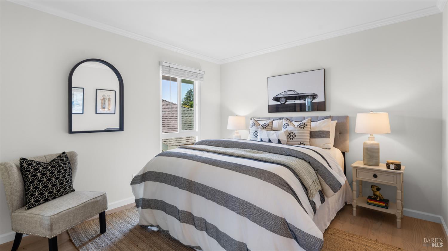 Staged bedroom with a large striped bed, patterned pillows, and framed car artwork.