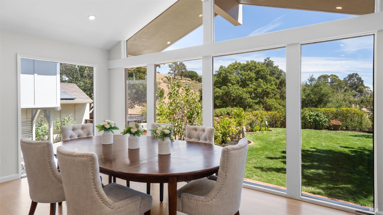 Dining room with a dark wood table and large windows overlooking the garden.