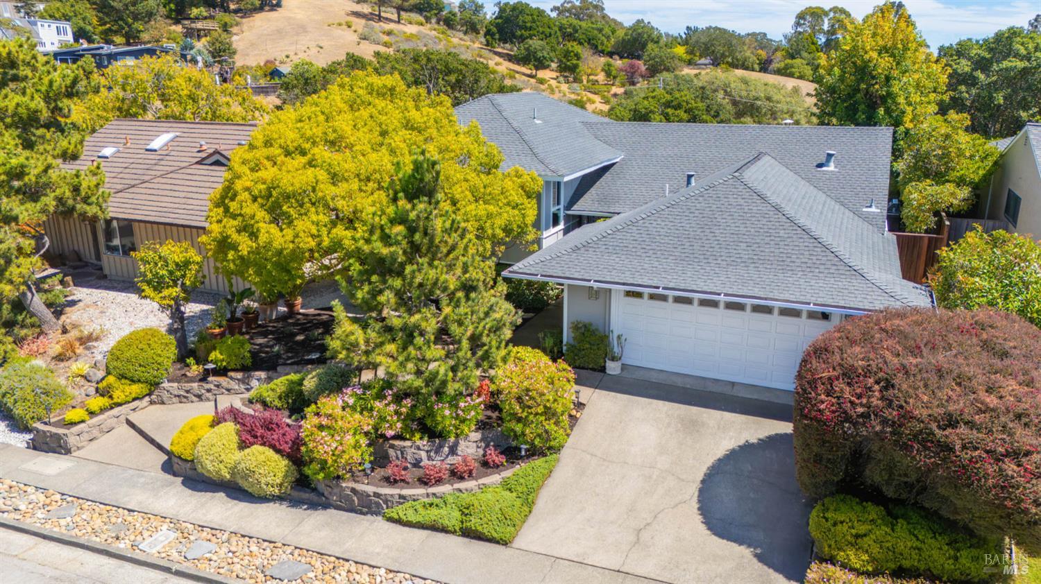 Home with a gray roof and two-car garage, surrounded by colorful landscaped gardens.