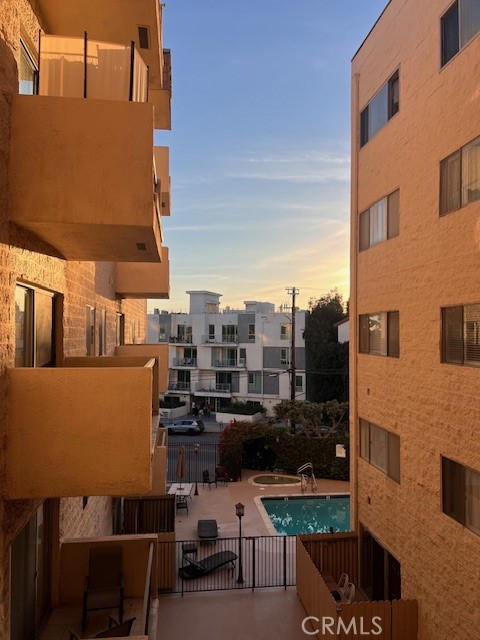 Apartment buildings frame a courtyard pool, seen from above in warm evening light.