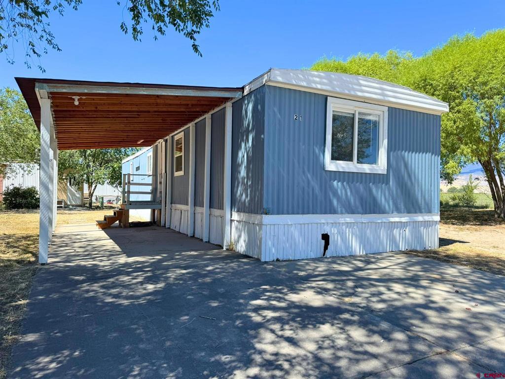 Blue manufactured home marked 21 with a covered porch and paved driveway.