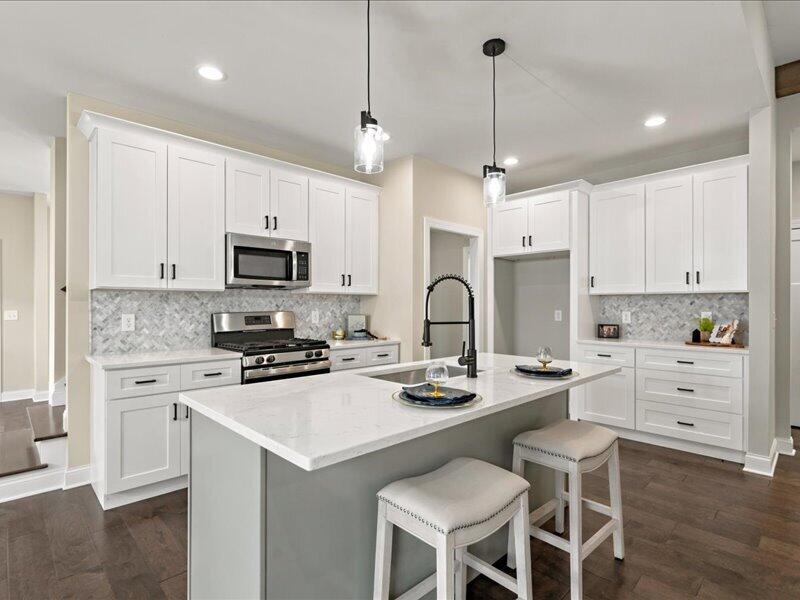 Modern kitchen with white cabinets, stainless steel appliances, and a large island with two stools.