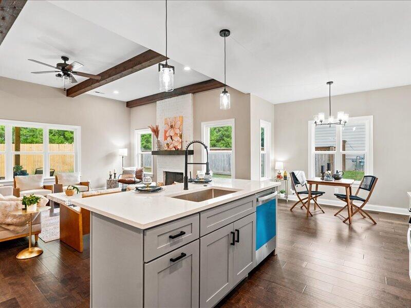 Open kitchen with a large white island, exposed beams, and adjoining living and dining areas.