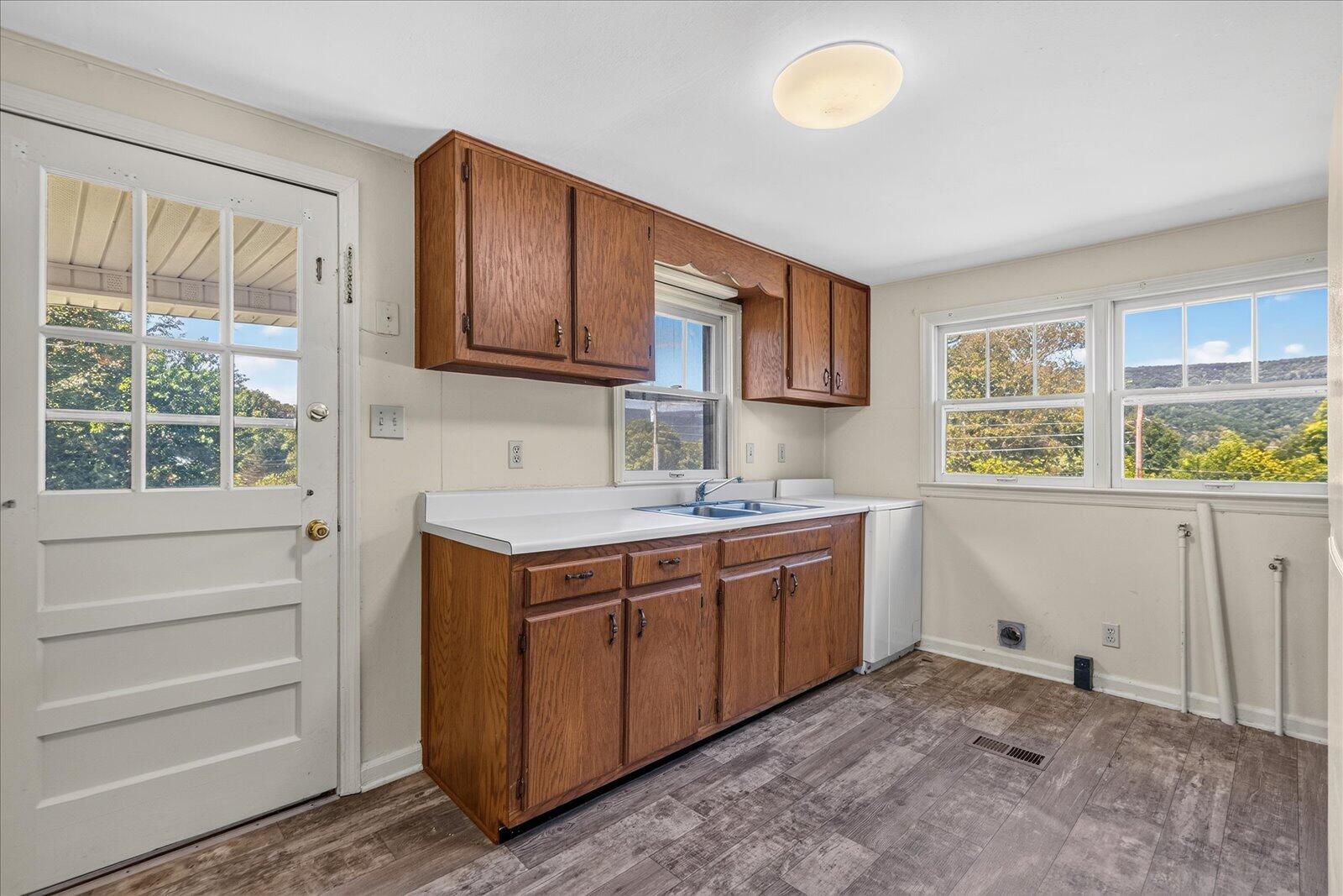 Kitchen with wood cabinets, a double-basin sink, and wooded hills visible through the windows.