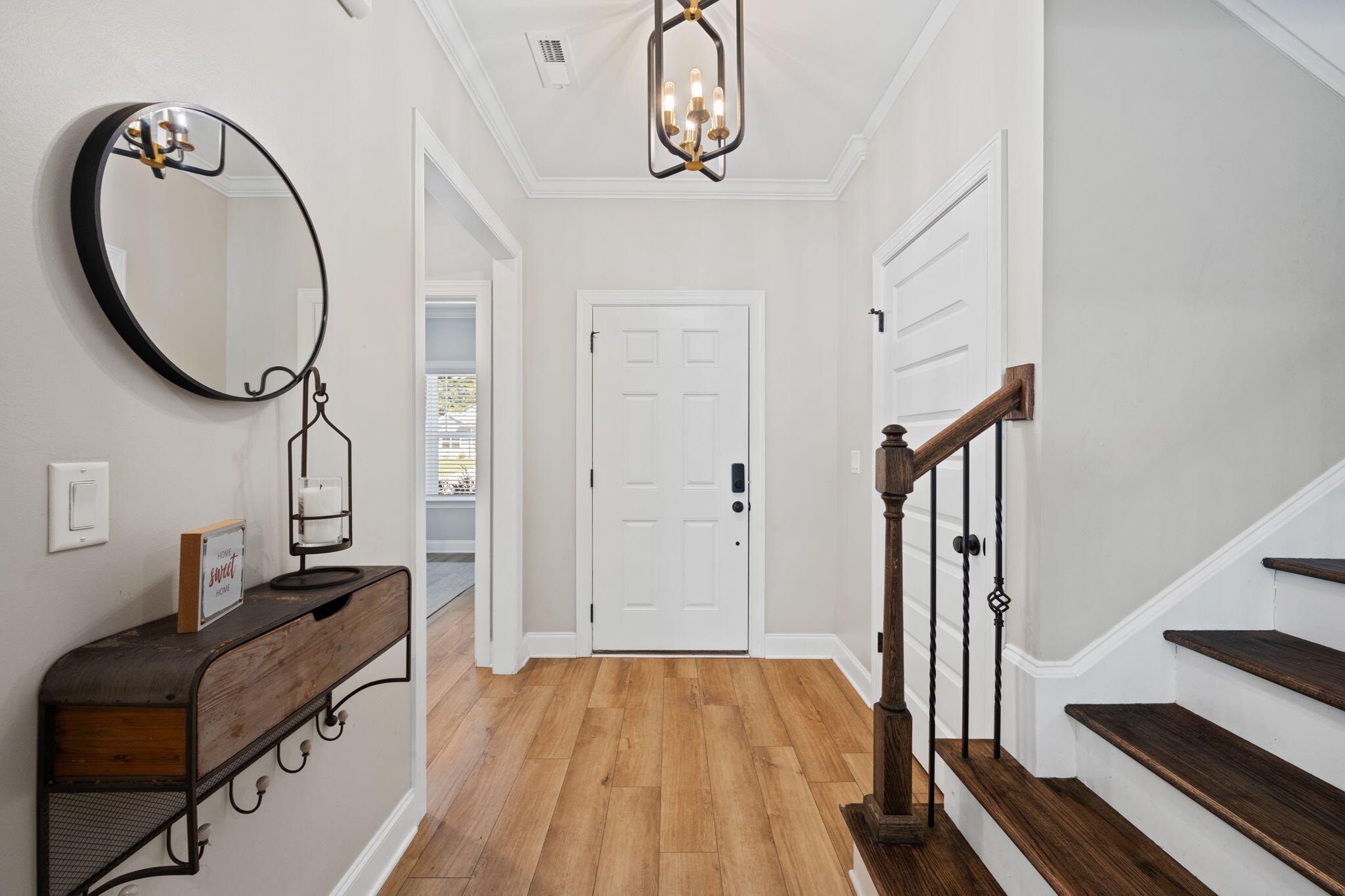 Entryway with a white front door, wood console table and mirror, and staircase with dark wood treads.