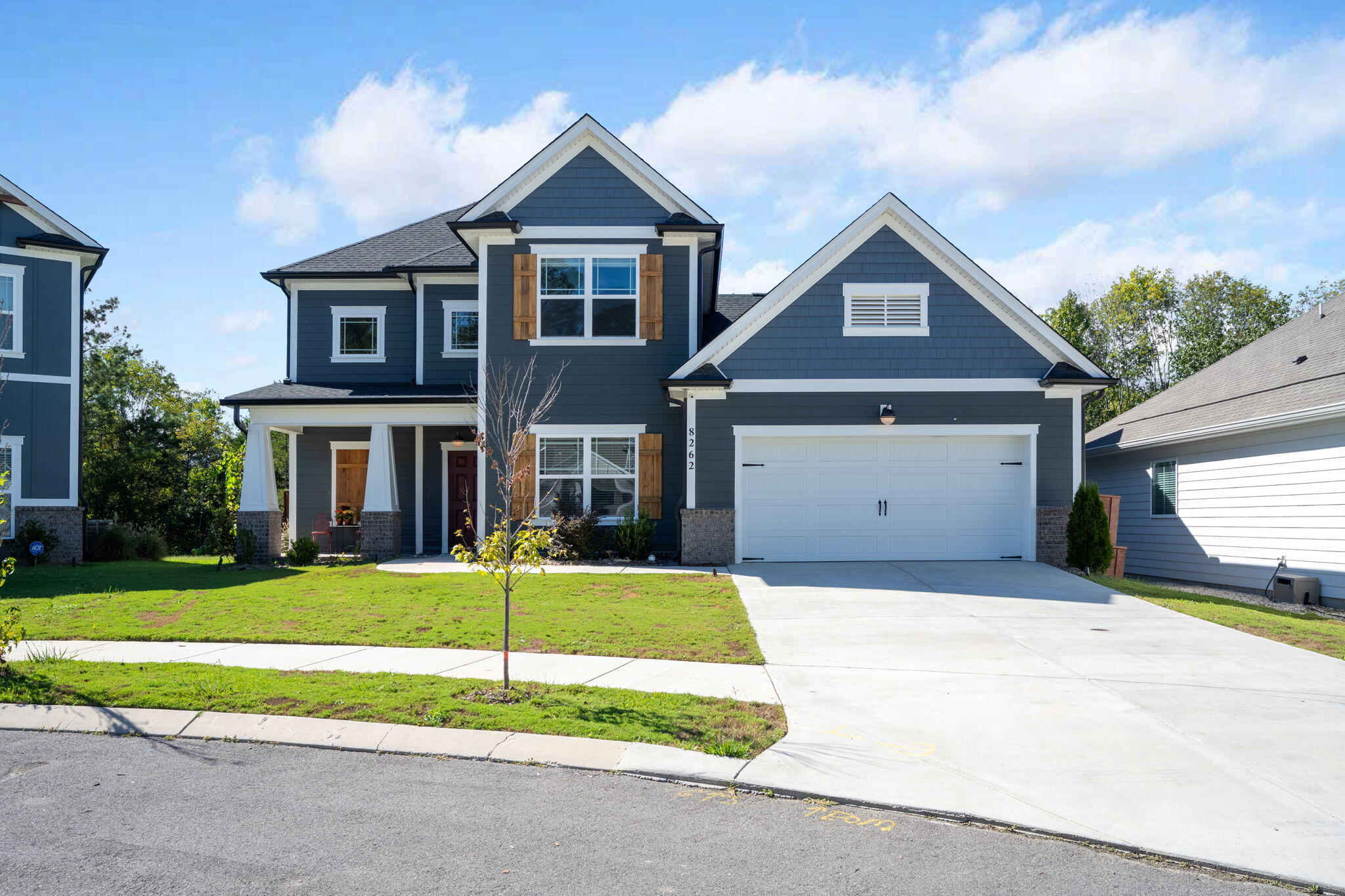 Dark blue two-story house with white trim, wood shutters, covered porch, and attached garage.