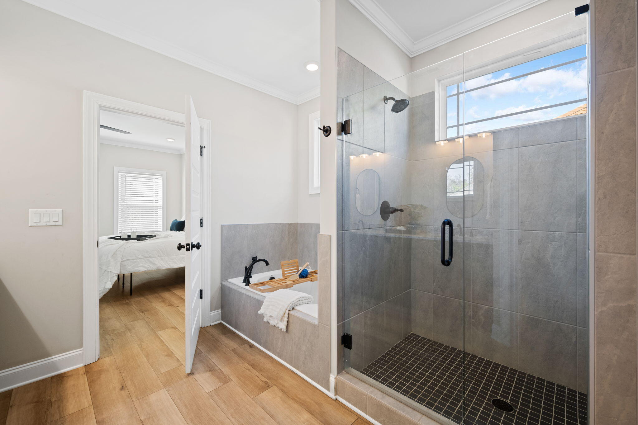 Bathroom with a glass walk-in shower and built-in soaking tub beside an open bedroom doorway.